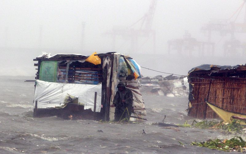 Olas gigantes chocan contra chabolas en el litoral de la Bahía Manila