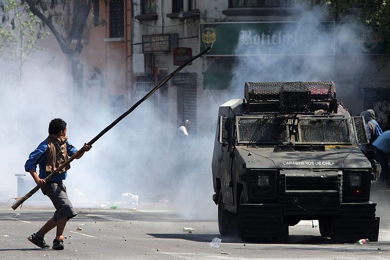 Un manifestante se enfrenta a un vehículo de policía durante las manifestaciones por la educación en Chile