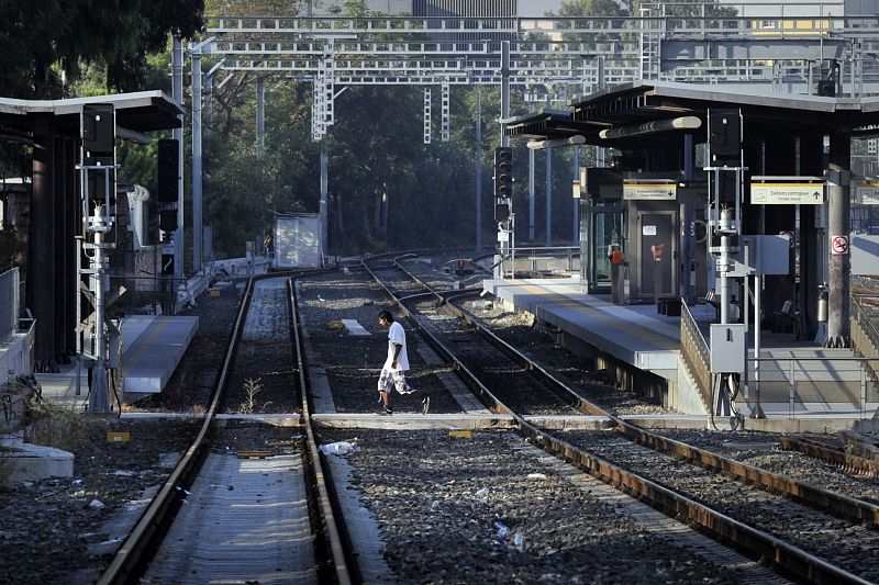 Un hombre cruza las vías de una estación de trenes de cercanías de Atenas