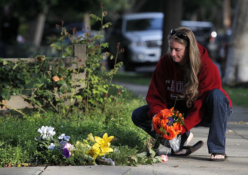 Una mujer coloca flores junto a la casa de Jobs en California.