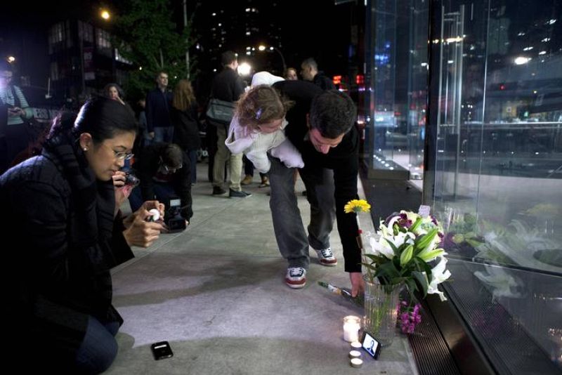 Dos personas colocan velas y flores en Nueva York. 