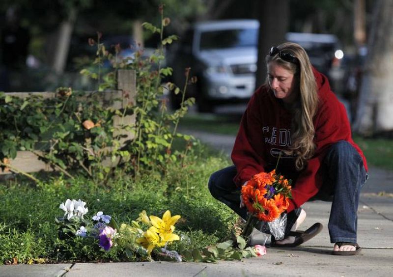 Una mujer coloca flores junto a la casa de Jobs en California.
