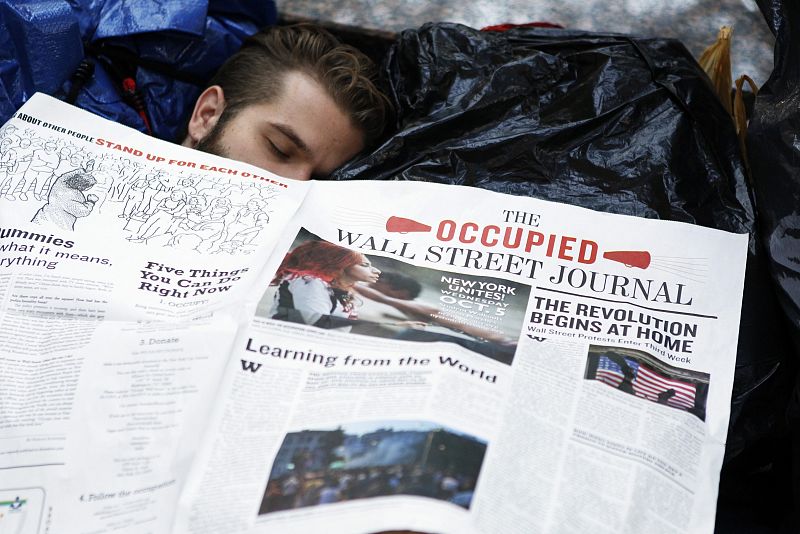 Un 'indignado' se tapa con el planfleto del movimiento mientras duerme en el lugar de acampada de Nueva York