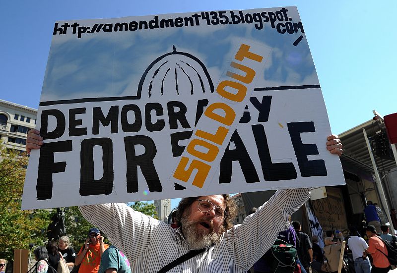 Un manifestante porta un cartel que compara la democracia con un inmueble en venta