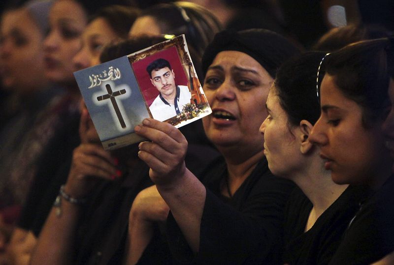 Una mujer muestra una fotografía de su hijo, uno de los fallecidos en los disturbios.