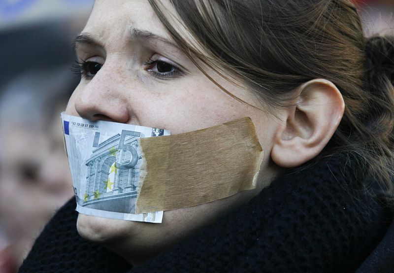 A protester shouts anti-capitalism slogans while her mouth is covered with a five Euro bill during a demonstration of several hundred people against banking and finance in Cologne