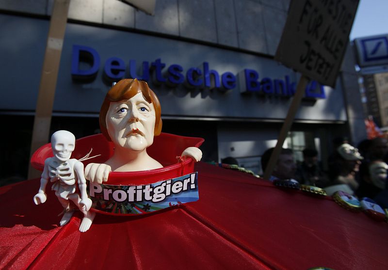 A figure of German Chancellor Merkel is pictured during a protest of several hundred people against banking and finance in front of a branch of Germany's largest bank Deutsche Bank in Cologne