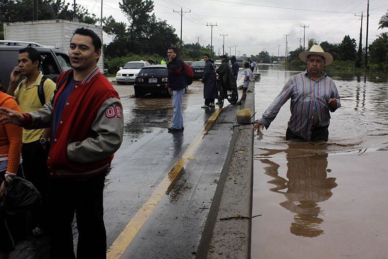 A man walks on a road that was flooded by the overflow of a river in the Ciudad Arce department of La Libertad