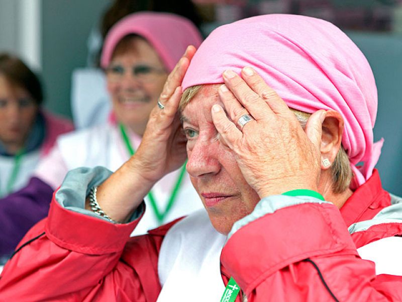 Una mujer se coloca un pañuelo rosa para participar en el lazo humano de Bilbao.