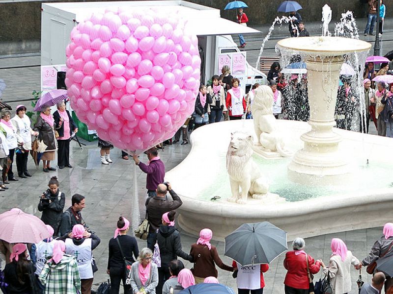 Decenas de personas construyen un lazo rosa en Bilbao.