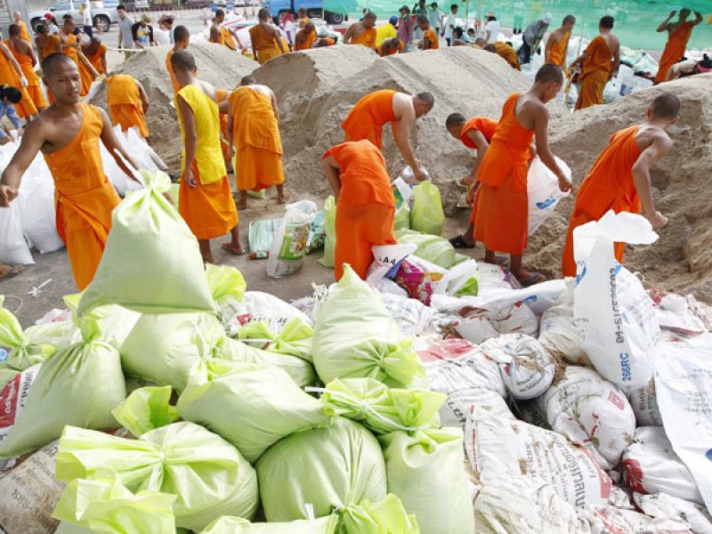Monjes budistas ayudan en las laborres de contención del agua en Pathum Thani, a unos 45km de la capital