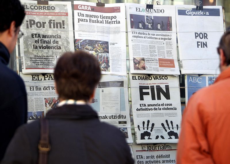 Varias personas leen en un kiosko de San Sebastián las portadas