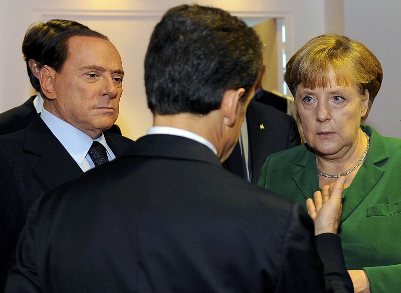 El presidente francés, Nicolas Sarkozy (de espaldas), habla con sus homólogos de Italia y Alemania, el primer ministro Silvio Berlusconi y la canciller Angela Merkel.
