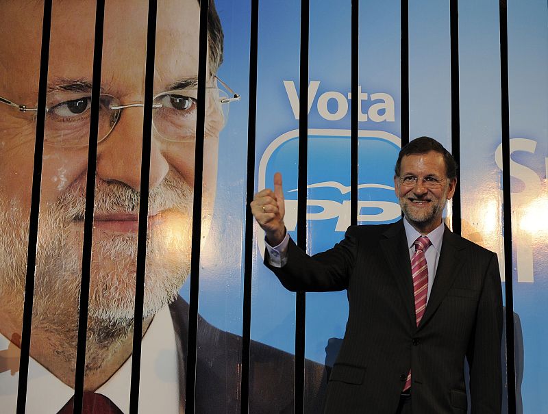 El candidato del PP a la presidencia del Gobierno pone su pulgar hacia arriba en frente de su cartel para las elecciones