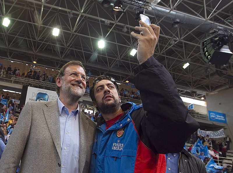 El candidato del PP, Mariano Rajoy, se hace una fotografía con un simpatizante.