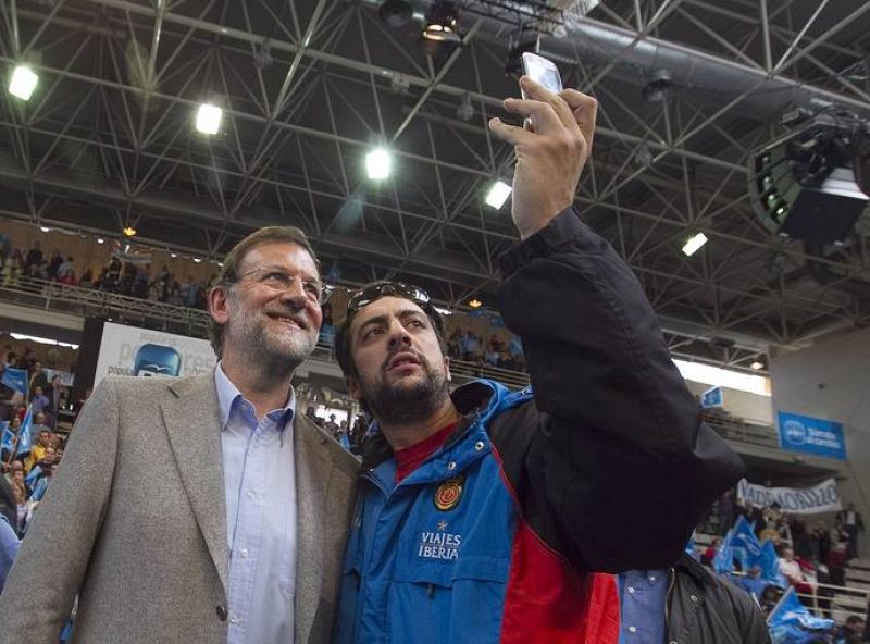 El candidato del PP, Mariano Rajoy, se hace una fotografía con un simpatizante.