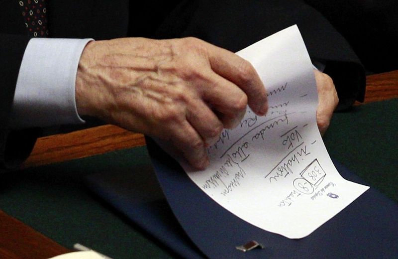 El primer ministro italiano, Silvio Berlusconi, sostiene una nota escrita por el mismo en la que puede leeerse "traidores", señalando a ocho de sus diputados
