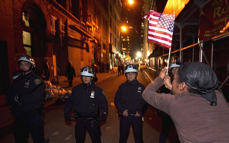 Uno de los miembros de Occupy Wall Street ondea una bandera ante el cordón policial