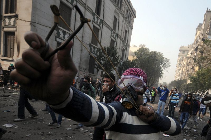 Un manifestante emplea tirachinas para tirar piedras contra la policía