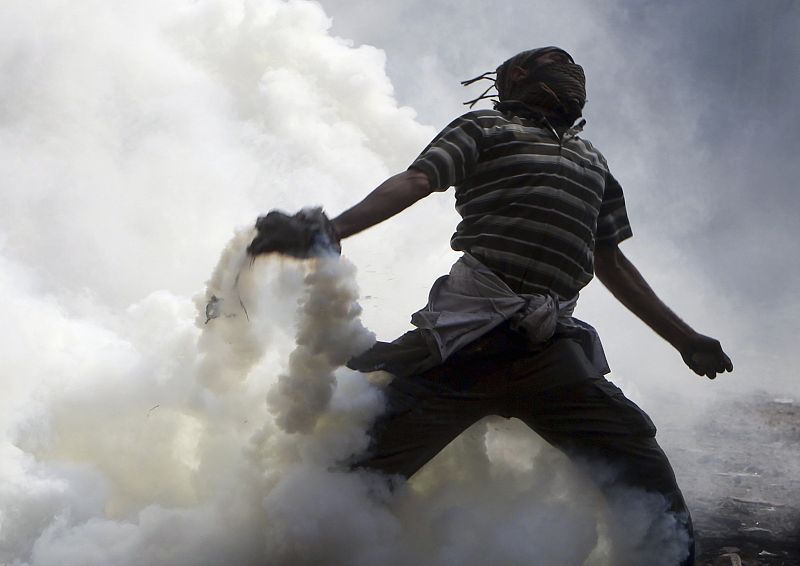 Un manifestante tira gases lacrimógenos contra los militares