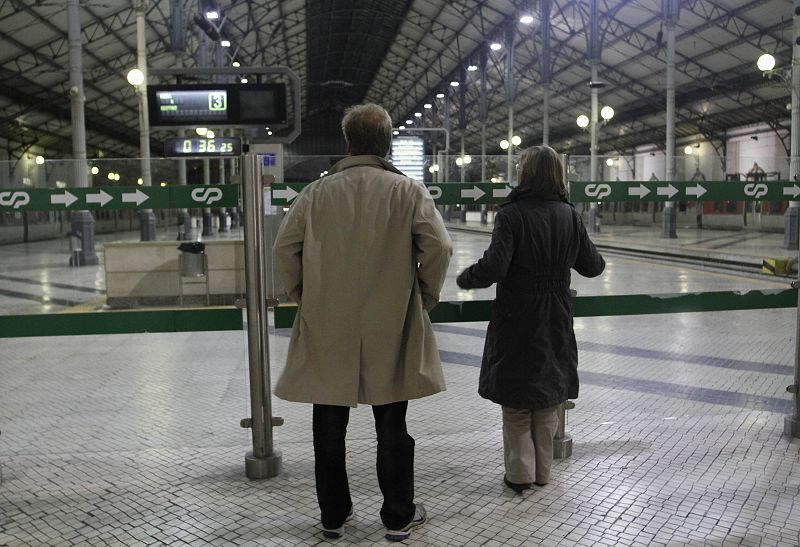 Dos personas en la estación de tren de Rossio de Lisboa, totalmente parada