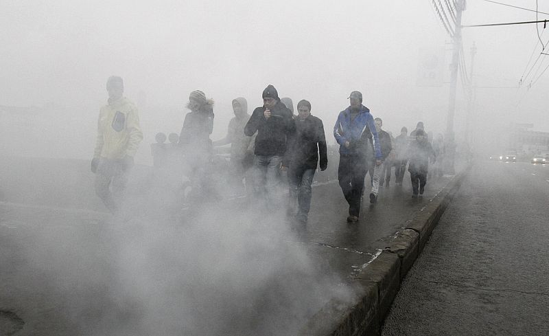 People walk amidst smoke from a flare in the city centre to attend a sanctioned rally in Bolotnaya square to protest against violations at the parliamentary elections in Moscow