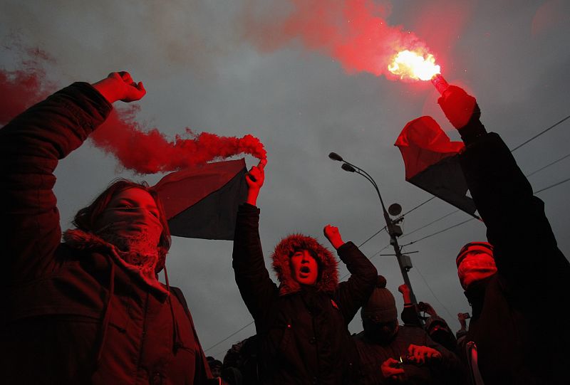 Members of a local anarchist movement burn flares during a sanctioned rally in Bolotnaya square to protest against violations at the parliamentary elections in Moscow