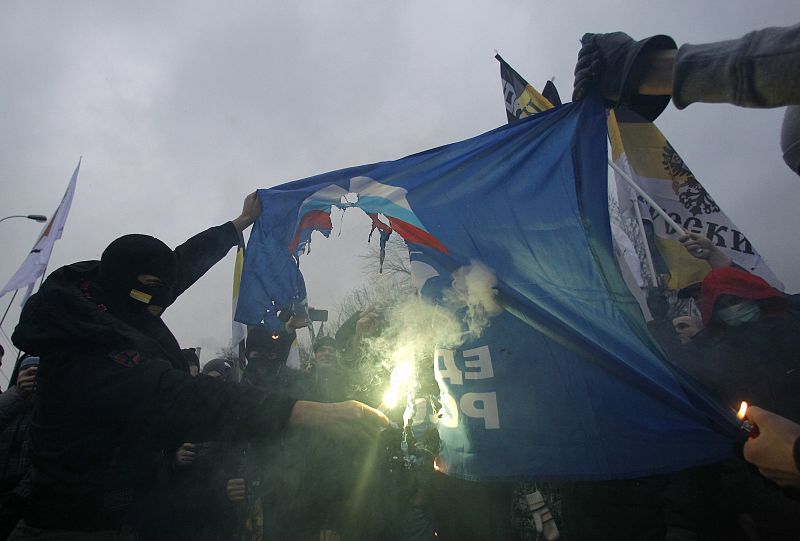 Russian nationalists burn a flag of the United Russia party during a sanctioned rally in Bolotnaya square to protest against violations at the parliamentary elections in Moscow