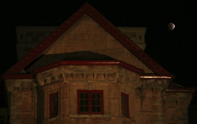 The earth's shadow falls on the moon during a total lunar eclipse next to the historic Amar Mahal museum in Jammu