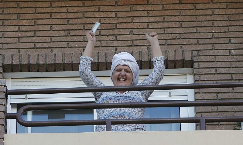 Una señora desde el balcón celebra que le ha tocado el quinto premio de la Lotería de Navidad.