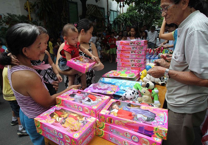 Mothers with their children choose free toys during a Christmas gift-giving session for children in Paranaque city