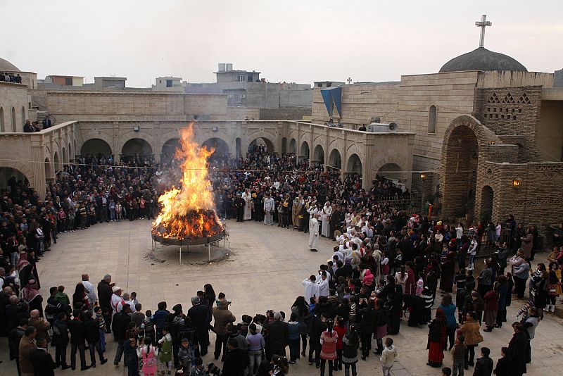 Iraqi Christians gather around a fire as they celebrate Christmas in a church in Hamdaniya town