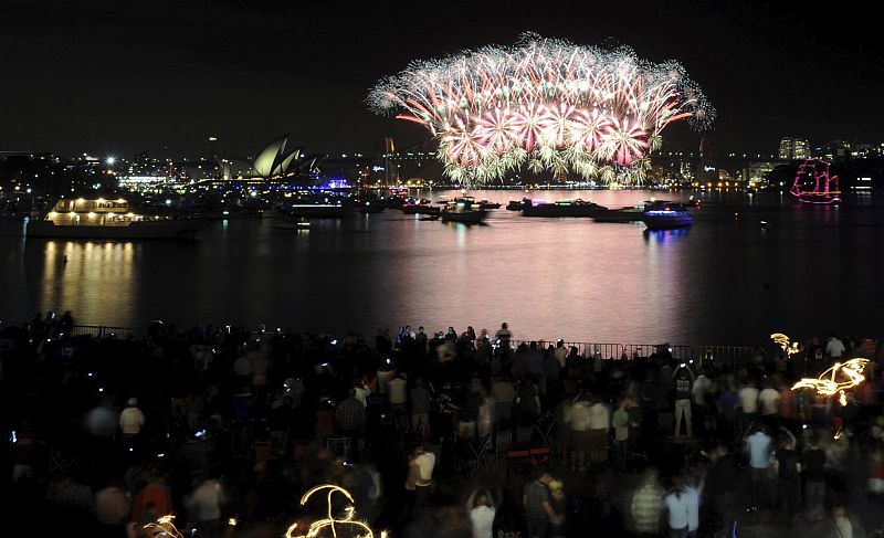 Los australianos disfrutan del espectáculo de fuegos artificiales para recibir al año 2012, en la bahía de Sydney.