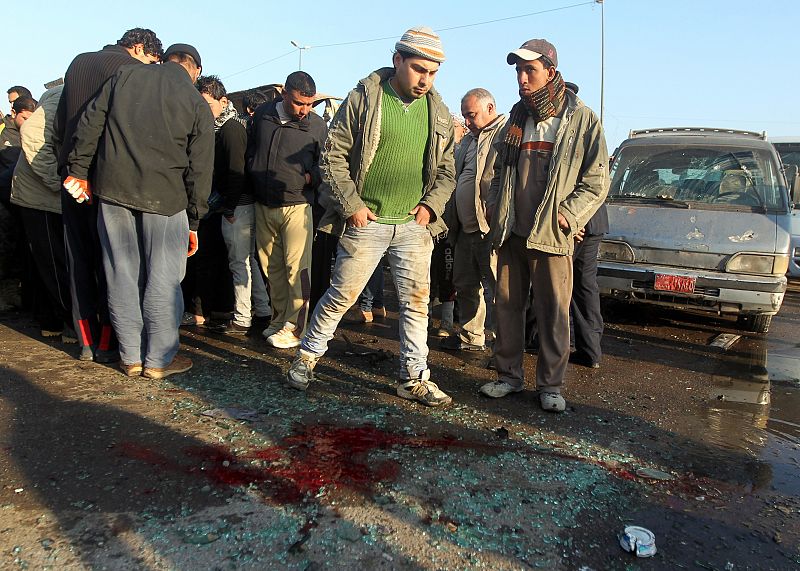 Iraquíes miran los restos de sangre y cristales rotos en la escena del atentado ocurrido en Ciudad Sadr.