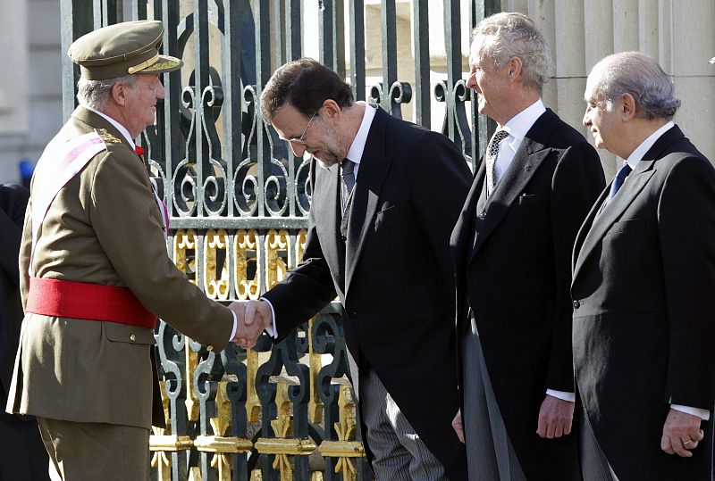 El rey Juan Carlos saluda al presidente del Gobierno, Mariano Rajoy, en presencia de los ministros de Defensa, Pedro Morenés (2-d), y de Interior, Jorge Fernández Díaz, en la Plaza de la Armería del Palacio Real.RNO