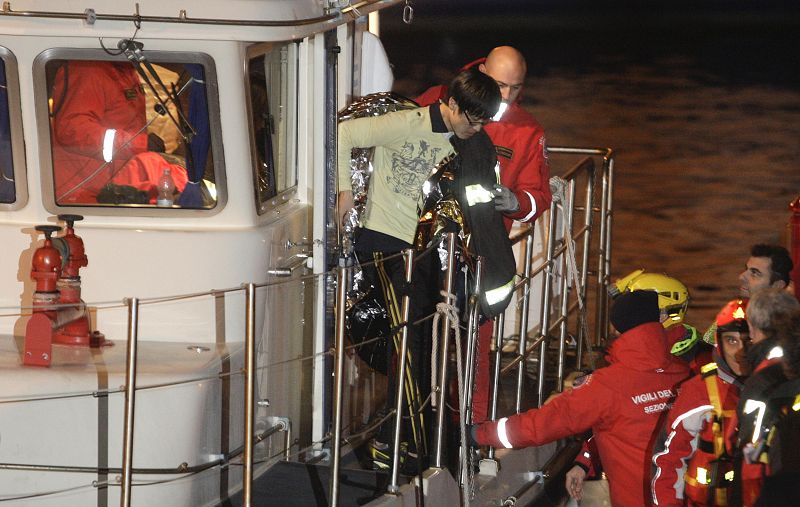 A South Korean man is helped after been rescued with his wife from Costa Concordia cruise as it ran aground off the west coast of Italy at Giglio island