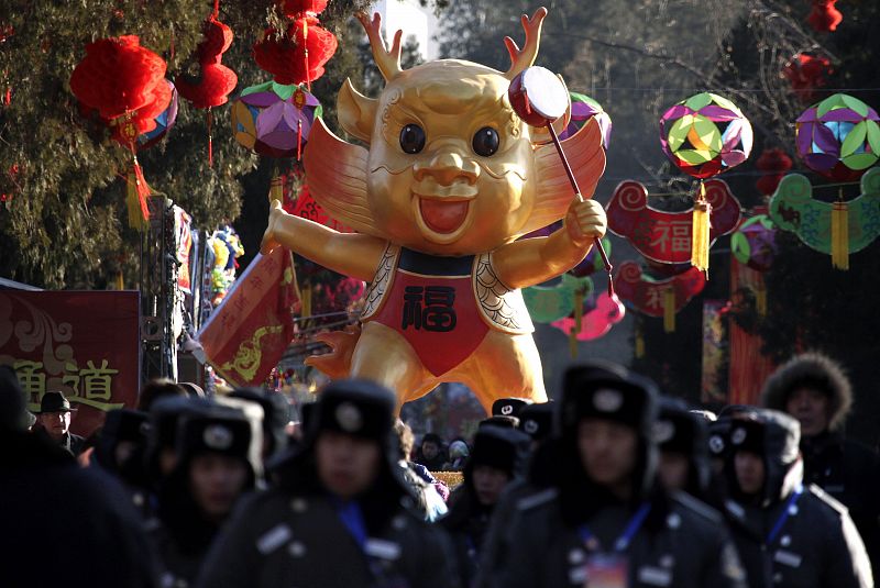 Security guards and police march past a large dragon doll before the opening of the temple fair at Ditan Park in Beijing