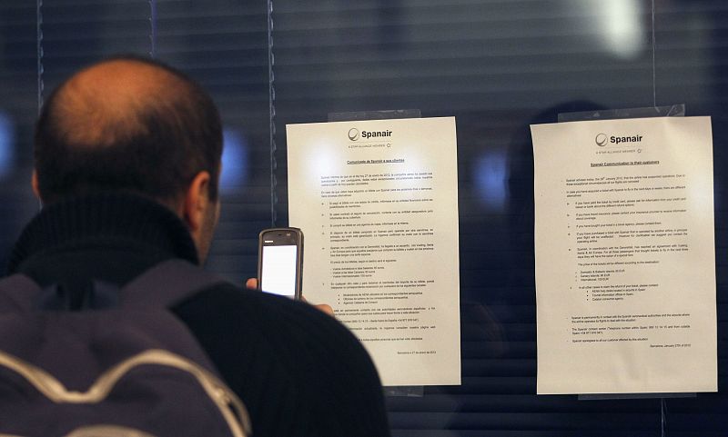 A passenger takes a photo of Spanair's claims instructions after the cancellation of flights, in front of Spanair's desk at Barcelona's airport