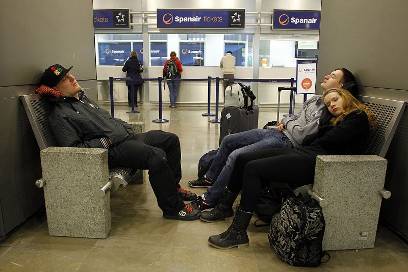 Spanair passengers make their claims at an Spanair ticket office as other passengers sleep at Madrid's Barajas airport