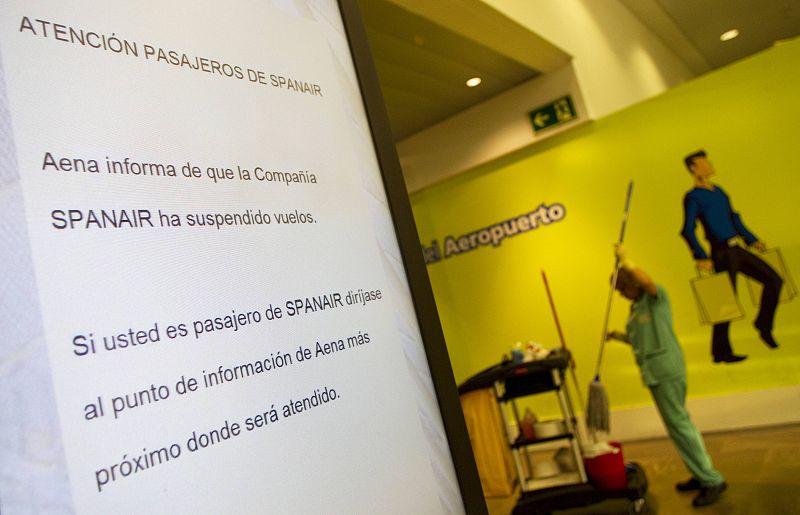 A worker cleans the floor next to a sign that announces passengers that Spanair has grounded its flights at Madrid's Barajas airport