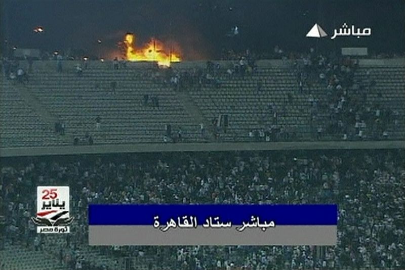 In this still image taken from video, soccer fans run near a fire at the stop of the stadium during a soccer match between Al Ahli and al-Masry in Port Said