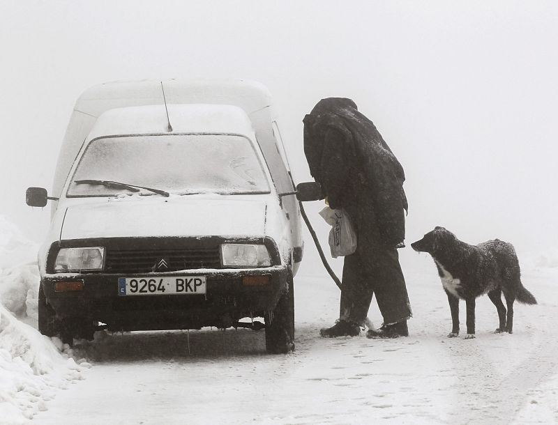 Un hombre intenta abrir la puerta de su coche rodeado de nieve