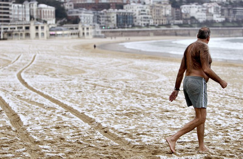 Un hombre se mete en el mar en la playa de La Concha en San Sebastián a pesar de la nieve