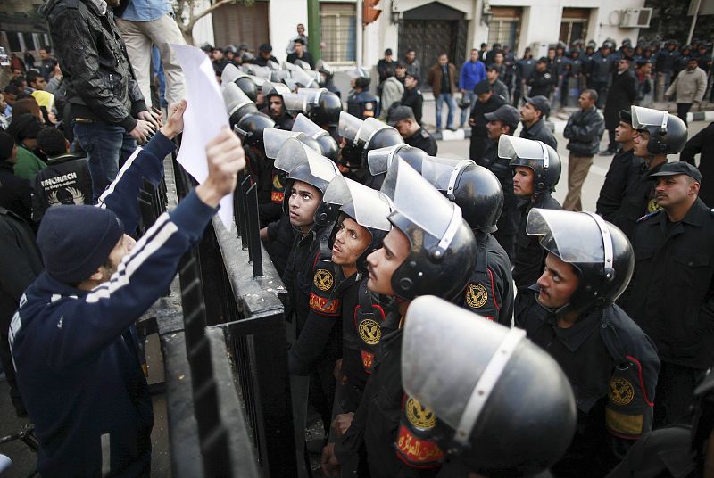 Riot police look at a banner held by a protester during a protest in Cairo