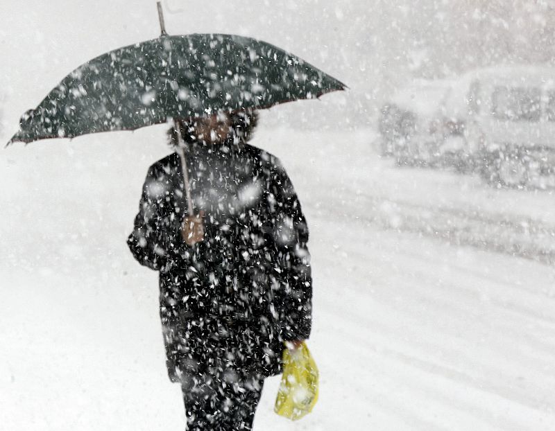 Una mujer camina en Cantabria en medio de una intensa nevada
