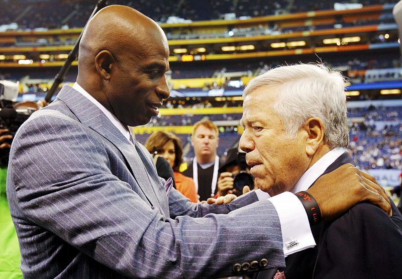 El propietario de los Patriots, Robert Kraft, saluda al ex jugador Deion Sanders