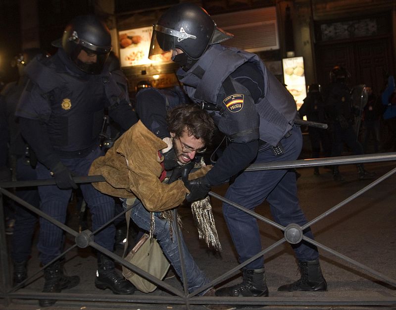 Spanish National Police officers in riot gear struggle with a protester during a demonstration against labour reform in Madrid