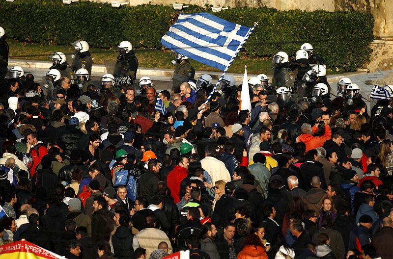 Anti-austerity protesters wave a Greek flag in front of the heavily guarded parliament in Athens' Syntagma square during a demonstration