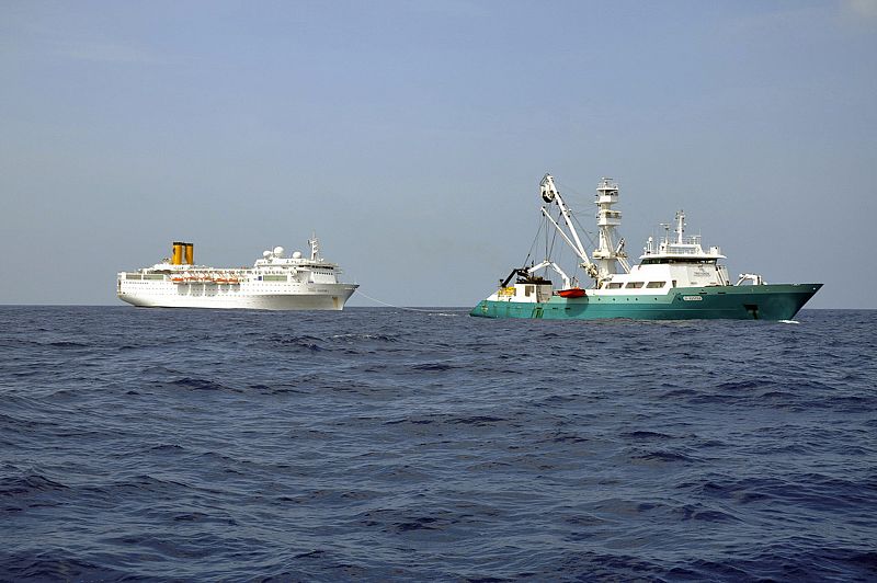 El Costa Allegra, sin propulsión, en una imagen tomada desde un barco francés. En primer término, el pesquero que le remolca.