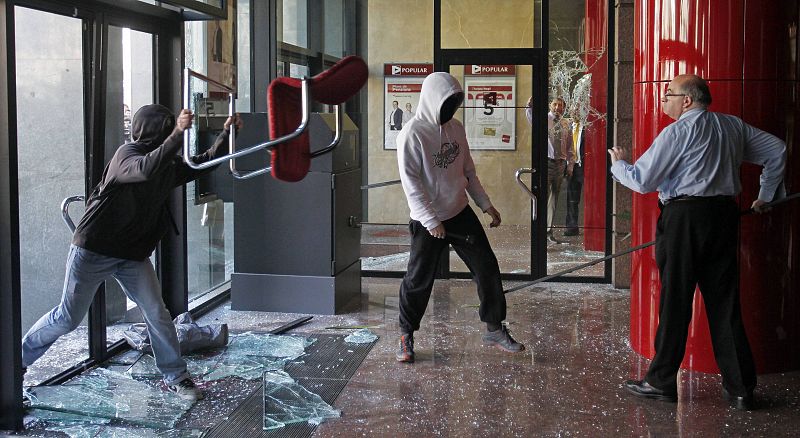 A man confronts protesters who were vandalising a bank facility during protests against cuts in education in Barcelona